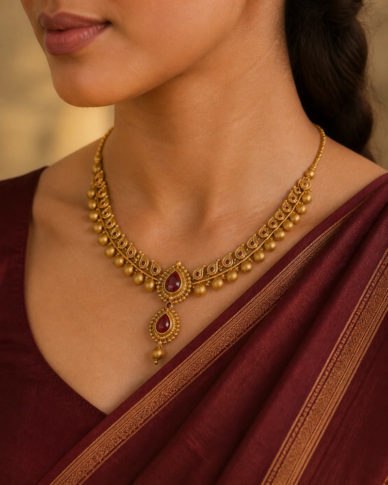 Gold necklace with red stones, worn by a model, lifestyle photo